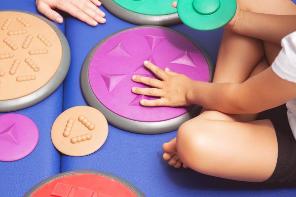Child with occupational therapist touching sensory integration equipment